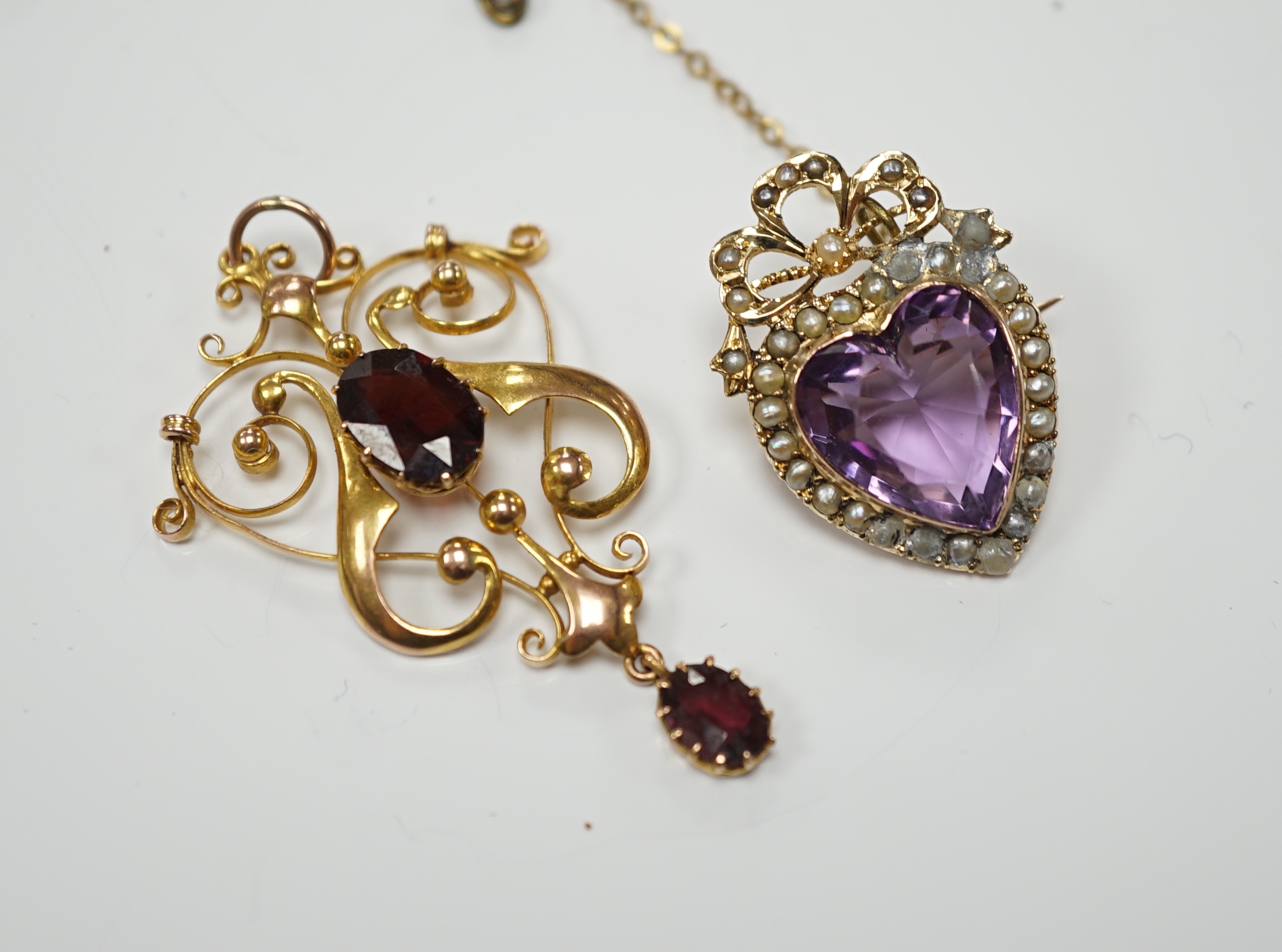 An early 20th century yellow metal, amethyst and seed pearl cluster set heart shaped brooch, 27mm, together with a similar yellow metal and two stone garnet set drop pendant, gross weight 9.3 grams.